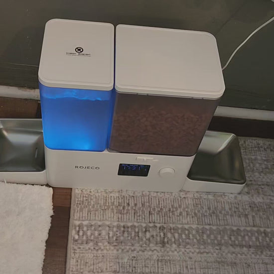 Image of the Rojeco 2-in-1 Automatic Cat Feeder and Water Dispenser featuring a 5L dry food container and a 3.5L gravity water system. The feeder includes stainless steel bowls for hygienic feeding and BPA-free construction to support pet health. The transparent containers allow easy monitoring of food and water levels, while the programmable feeding function enables controlled meal portions throughout the day. LED indicator alerts help ensure consistent food flow, and dual power support (Type-C and AAA bat